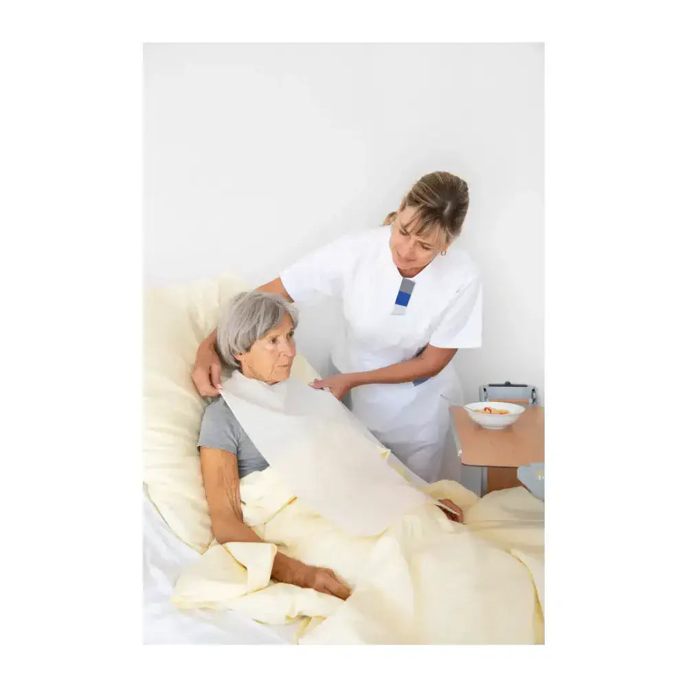 einweg essschürze 3-lagig wasserdicht bei Patientin im Bett, Pflegekraft legt Essschürze an, hygienischer Kleidungsschutz
